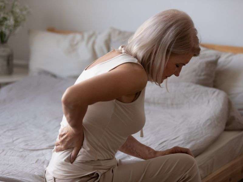 Frau mit Rückenschmerzen, die ihre steifen Muskeln reibt